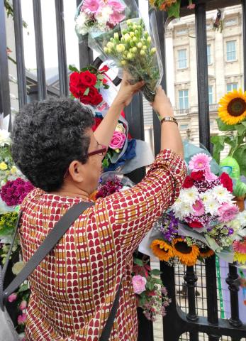 Sister Eugine Simon puts flowers outside Buckingham Palace 