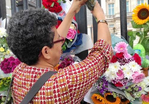 Sister Eugine Simon puts flowers outside Buckingham Palace 