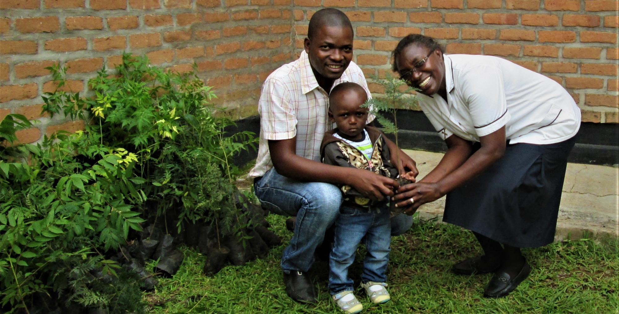 A small boy and his father take a tree to plant at home